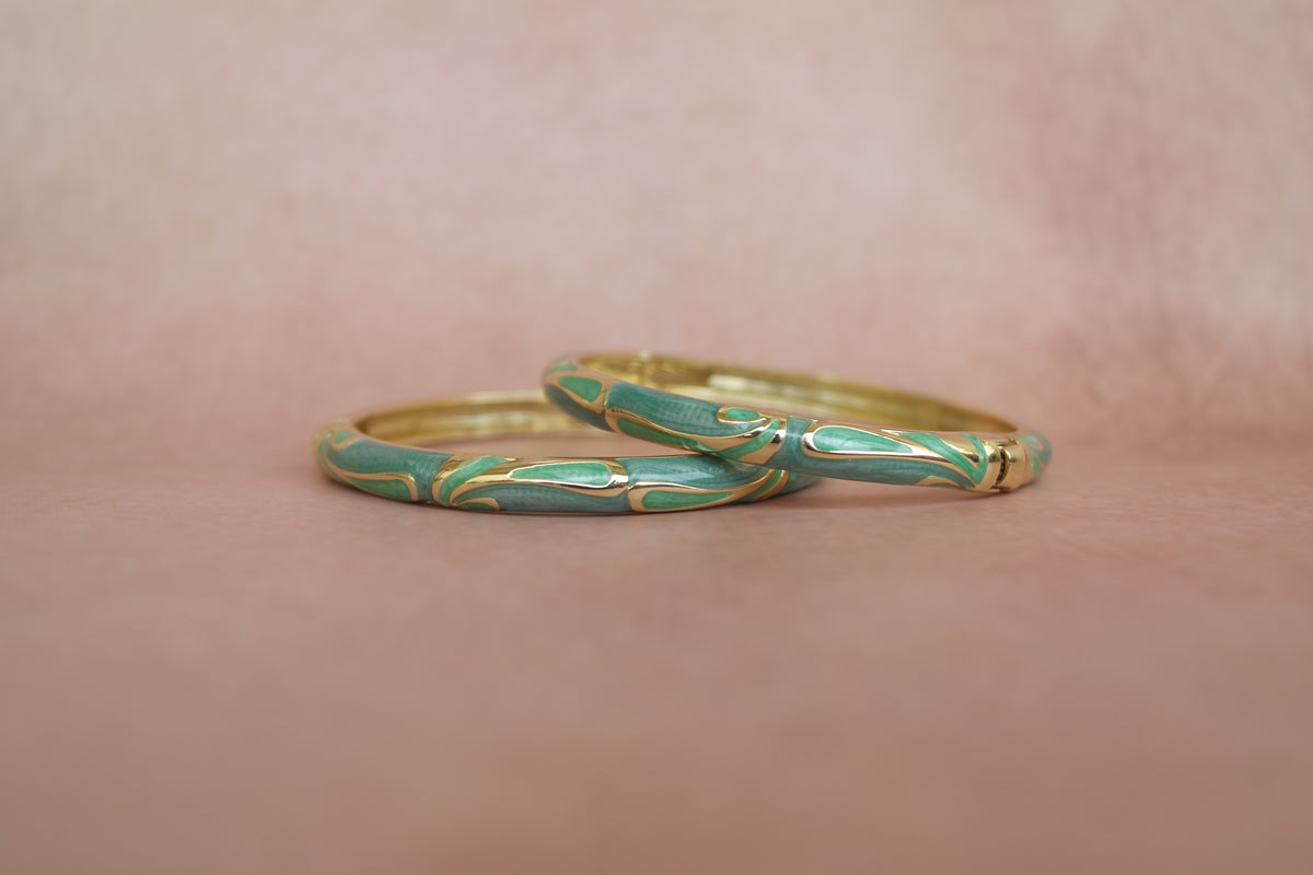 Tarang enamel bangle by Rangat — flowing gold strokes move across deep green enamel