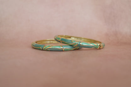 Tarang enamel bangle by Rangat — flowing gold strokes move across deep green enamel